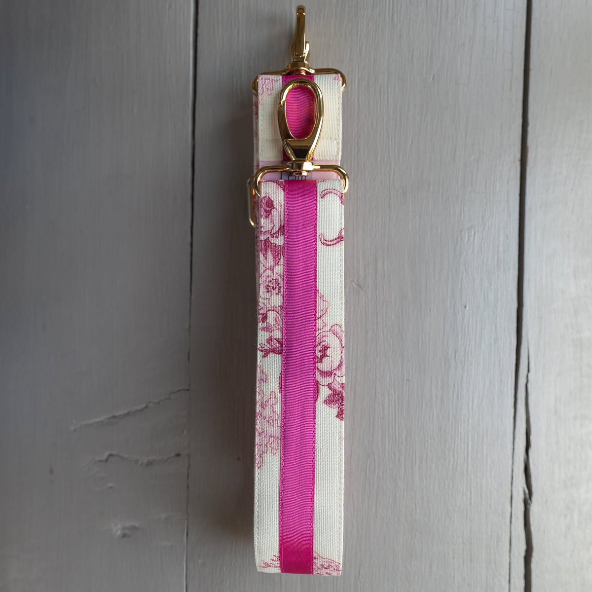 Taschengurt Helene Rosa in Toile de Jouy mit pinkem Ripsband und goldfarbenen Karabinern.